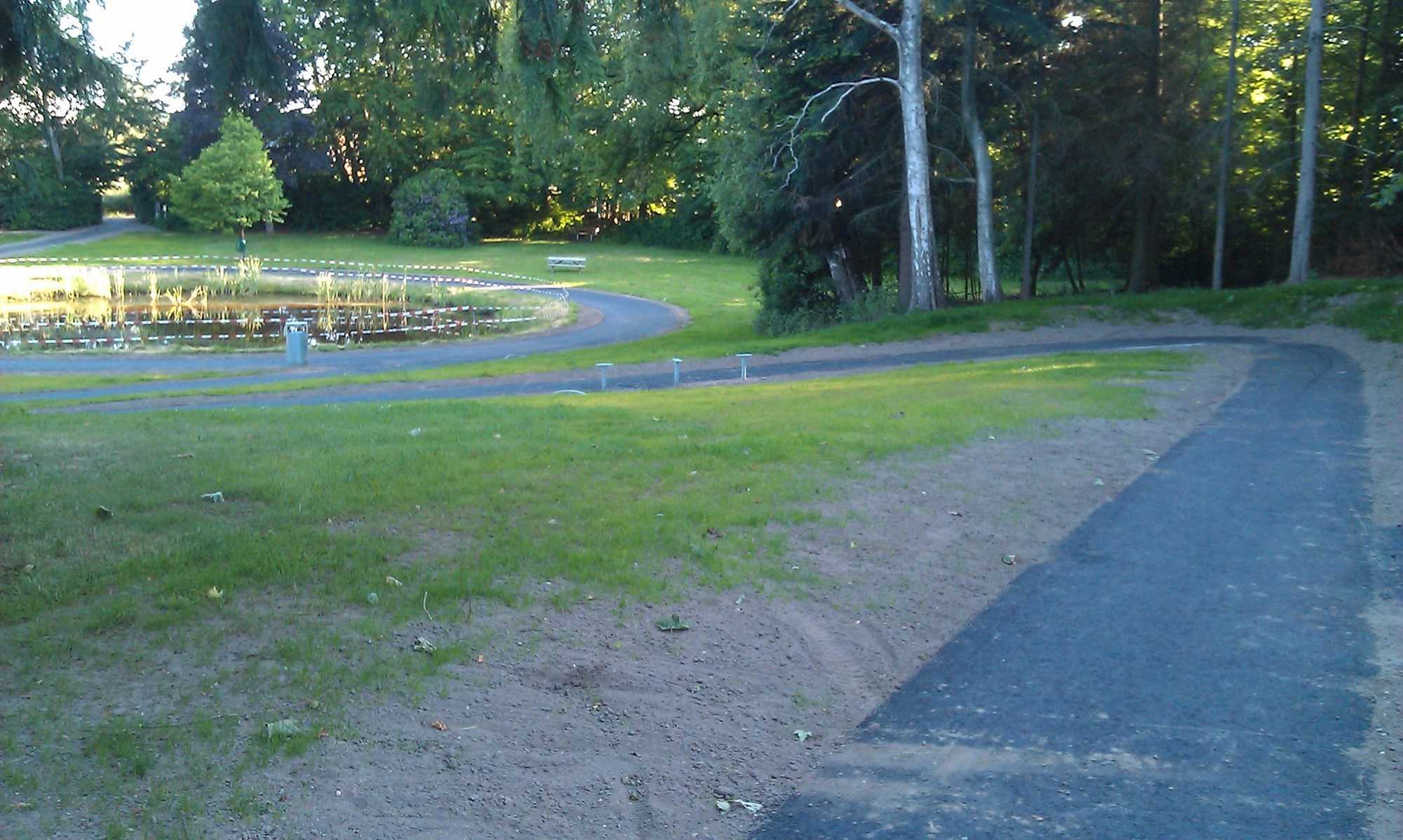 Asfaltsti, park og lille sø